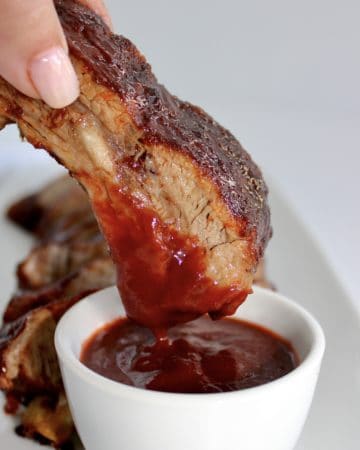 rib being dipped into bbq sauce