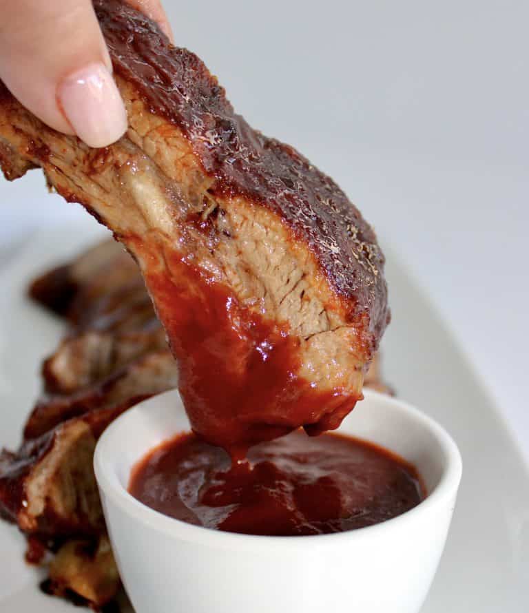 rib being dipped into bbq sauce