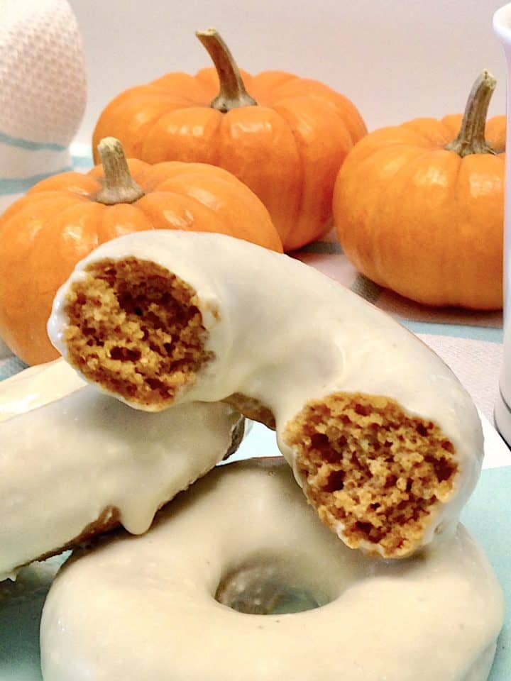 Keto Pumpkin Donuts with one cut open and pumpkins in background