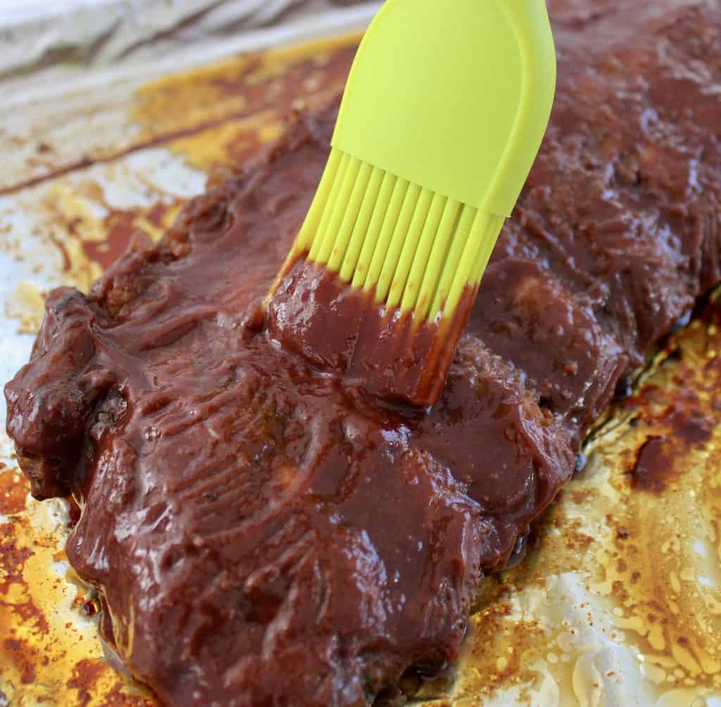 Keto Raspberry Chipotle BBQ Sauce being brushed over ribs