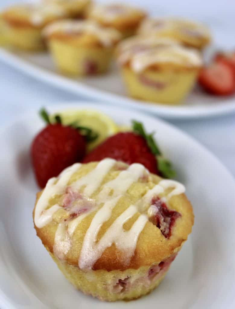 Keto Strawberry Lemonade Muffins with icing on top and strawberries on side