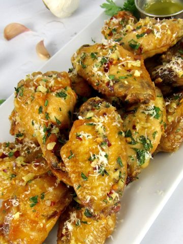 Parmesan Garlic Wings on white plate with butter dipping sauce on side