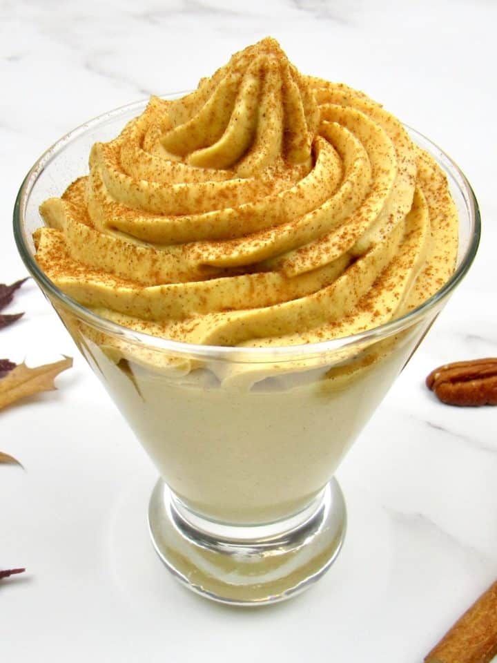 Pumpkin Cheesecake Mousse in fancy glass with pecans in the background