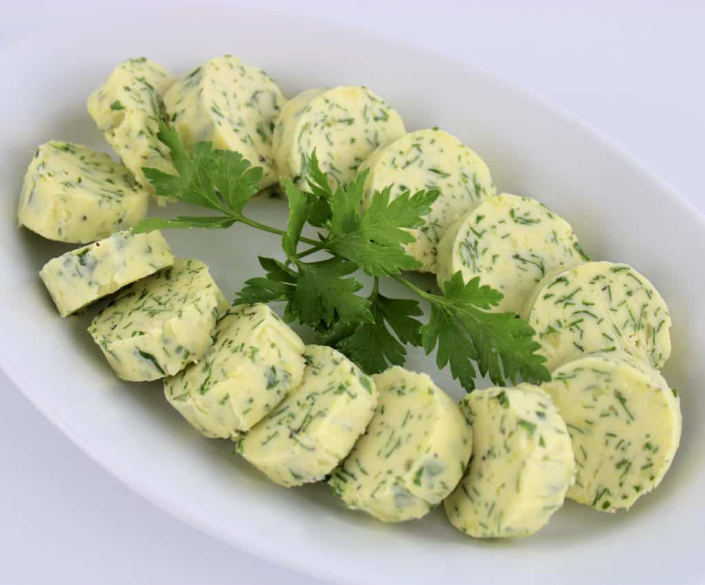 Garlic Herb Compound Butter arranged in a circle on white plate parsley in center