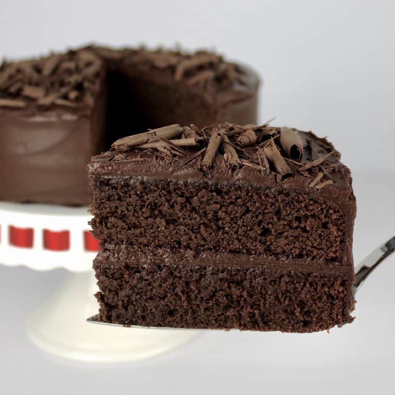 slice of Keto Chocolate Cake being held up with cake in background