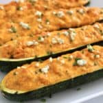 Buffalo Chicken Zucchini Boats on white plate with blue cheese on top