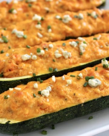 Buffalo Chicken Zucchini Boats on white plate with blue cheese on top