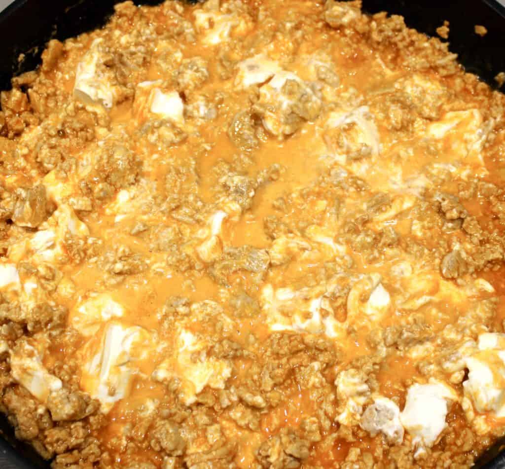 ground buffalo chicken with chunks of cream cheese in skillet