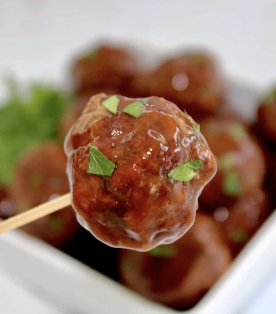 closeup of bbq meatball on skewer with meatballs in background