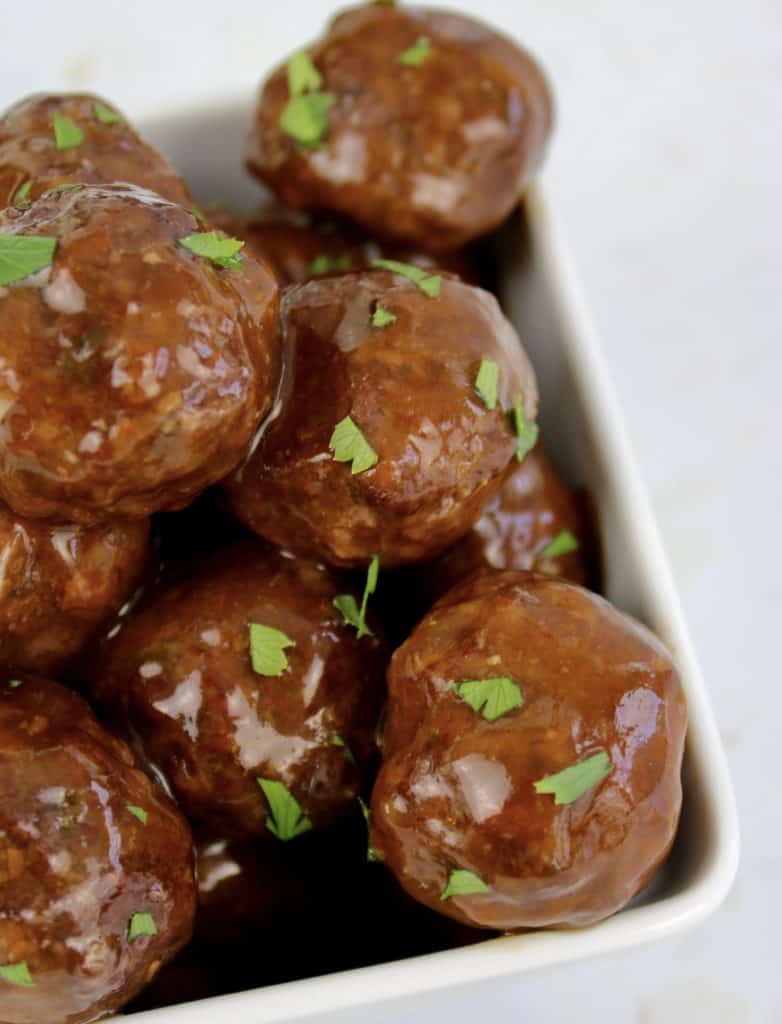 closeup of bbq meatballs in white bowl with parsley on top