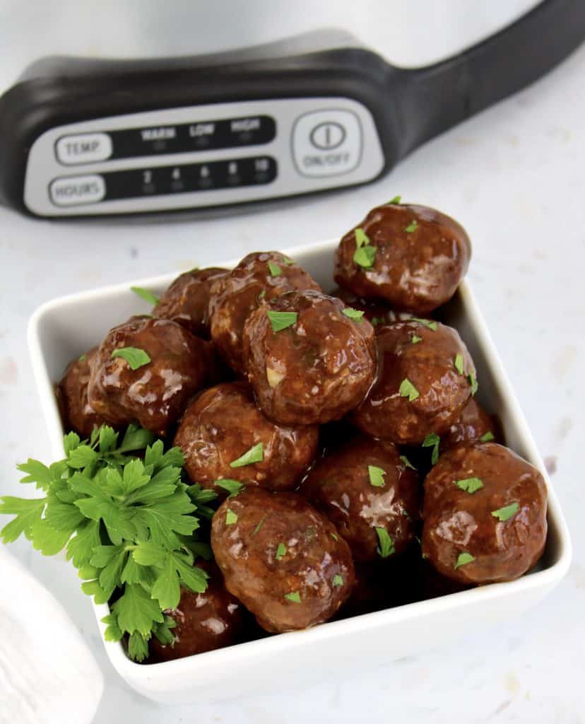 crockpot bbq meatballs in white bowl with crockpot in background