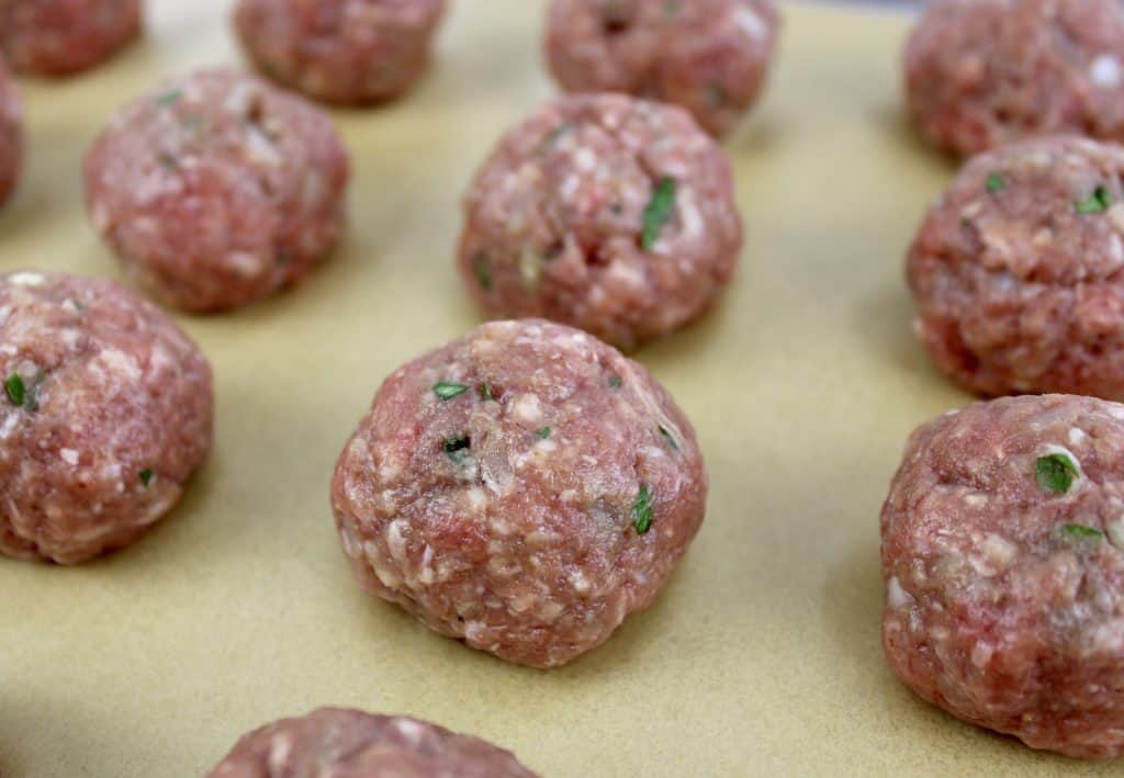 closeup of crockpot bbq meatballs unbaked on baking sheet