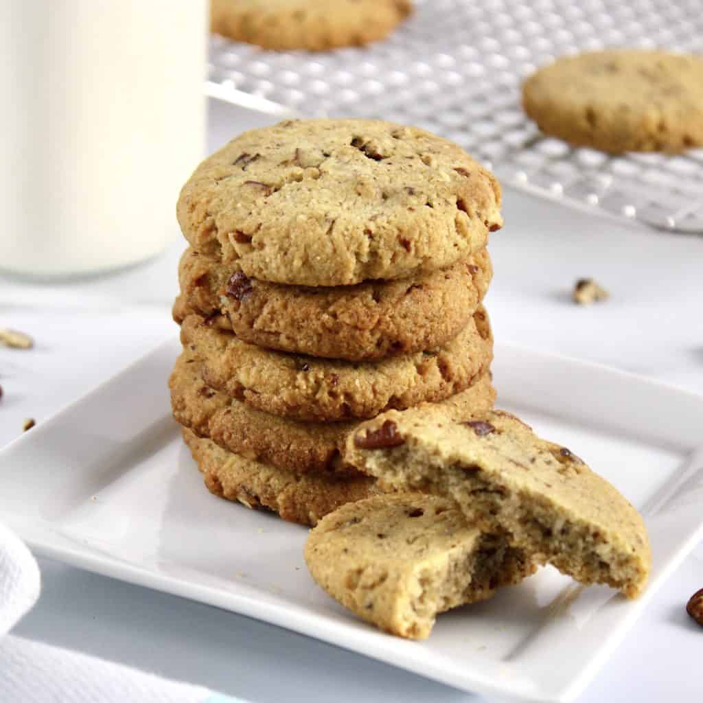 stack of butter pecan cookies on white plate with one broken cookie