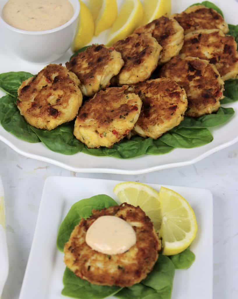 crab cakes on white plate over bed of spinach