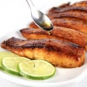 Maple Glazed Salmon on white plate with maple syrup being spooned over top