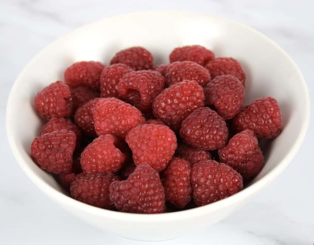 raspberries in white bowl