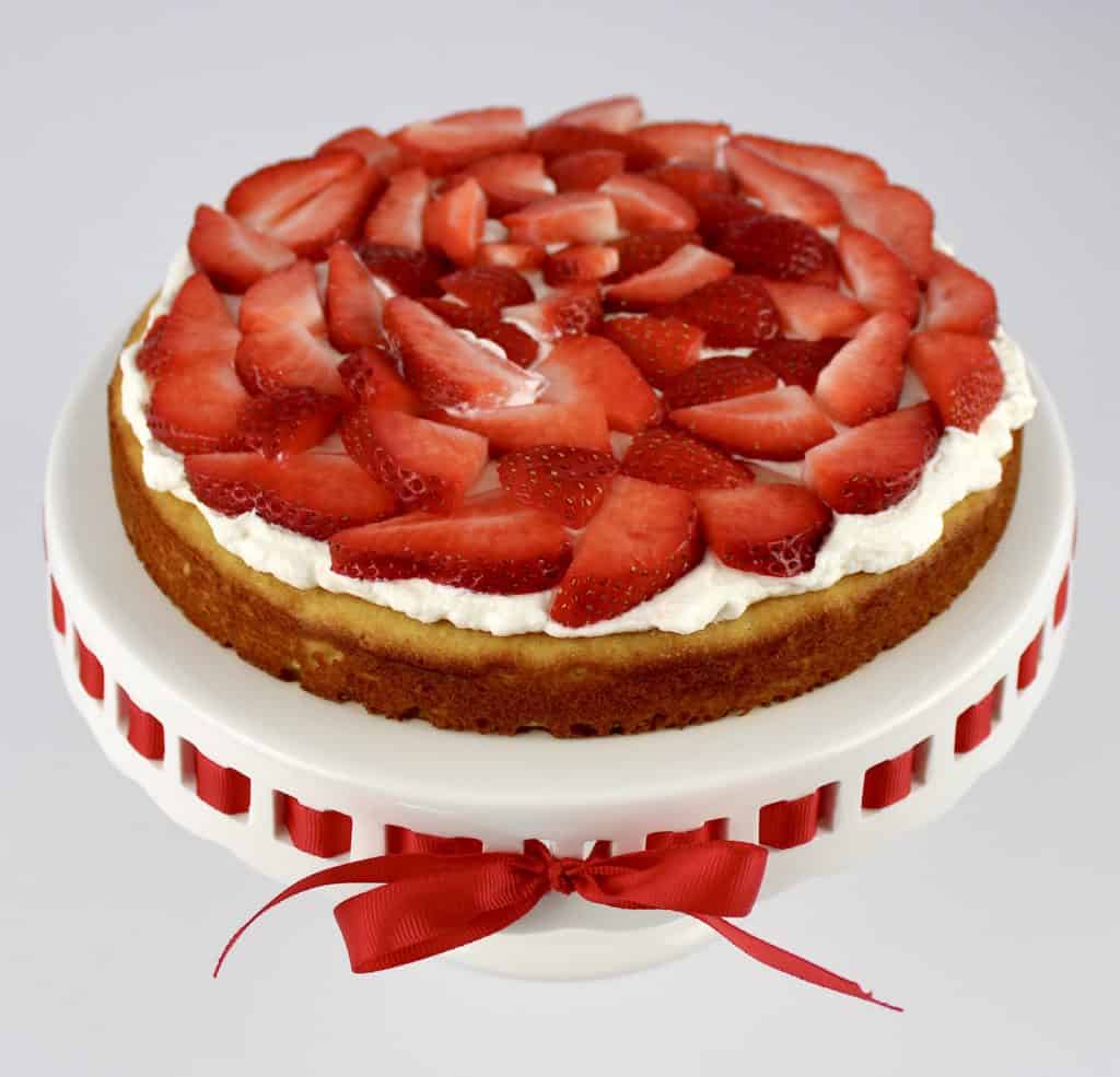 strawberry shortcake with sliced strawberries on top of cake stand