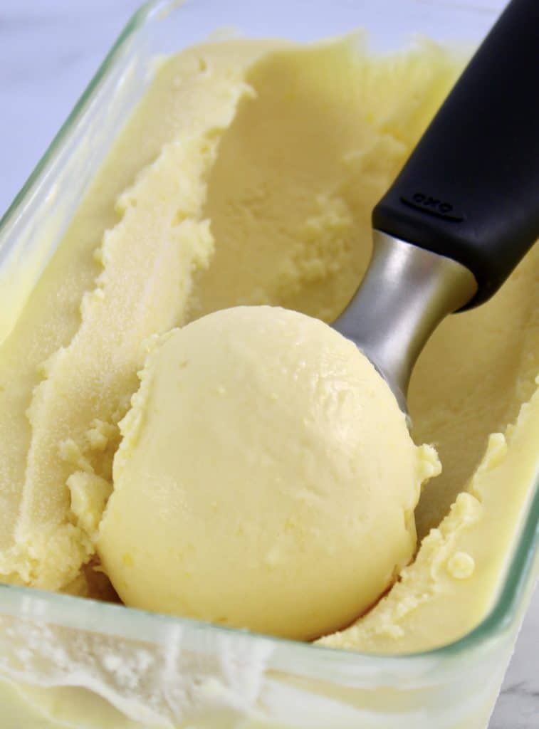 lemon ice cream in glass container with scoop