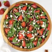 overhead view of strawberry spinach salad with dressing on top