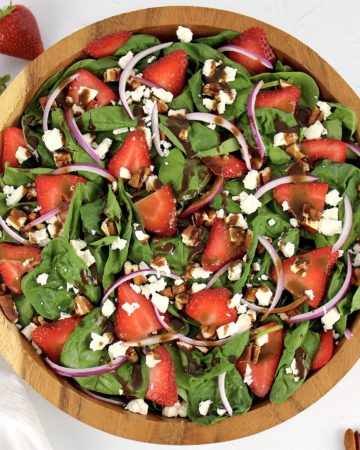 overhead view of strawberry spinach salad with dressing on top
