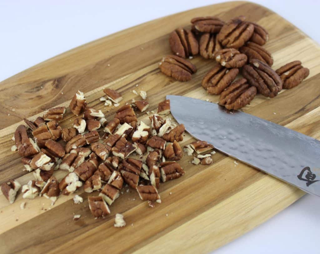 chopped pecans on cutting board with knife