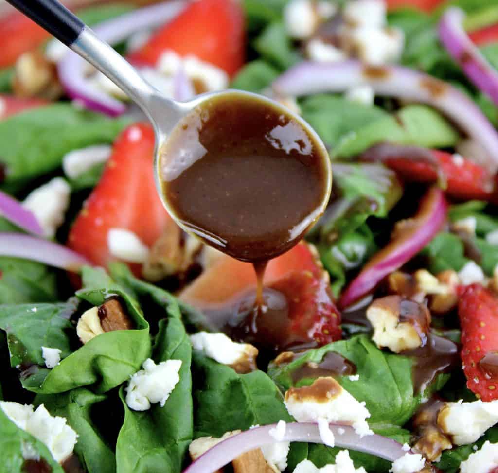 Strawberry Spinach Salad with Balsamic Vinaigrette being spooned over top