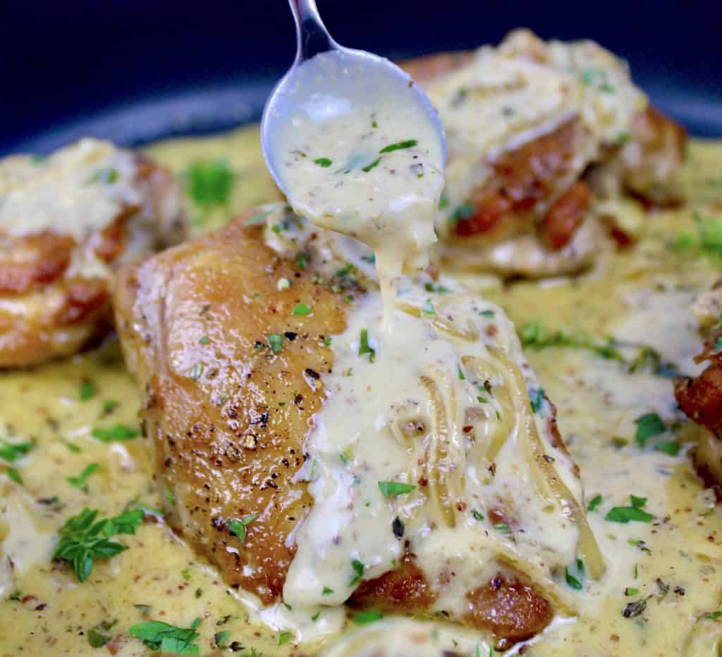 chicken dijon in skillet with sauce being spooned over top