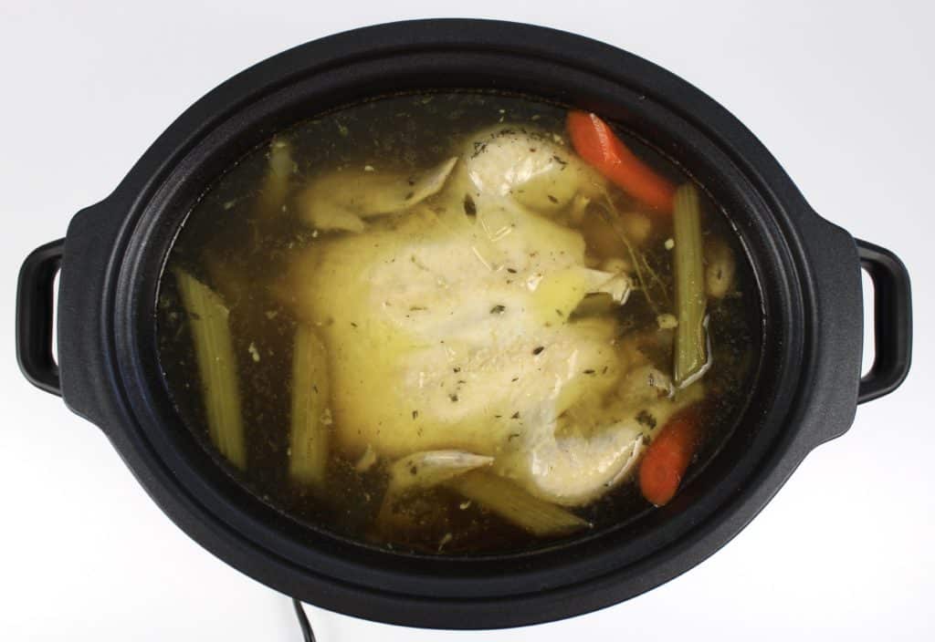 cooked chicken broth in crockpot with whole chicken