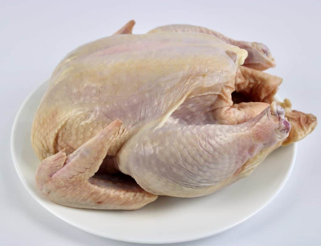 whole raw chicken on white plate