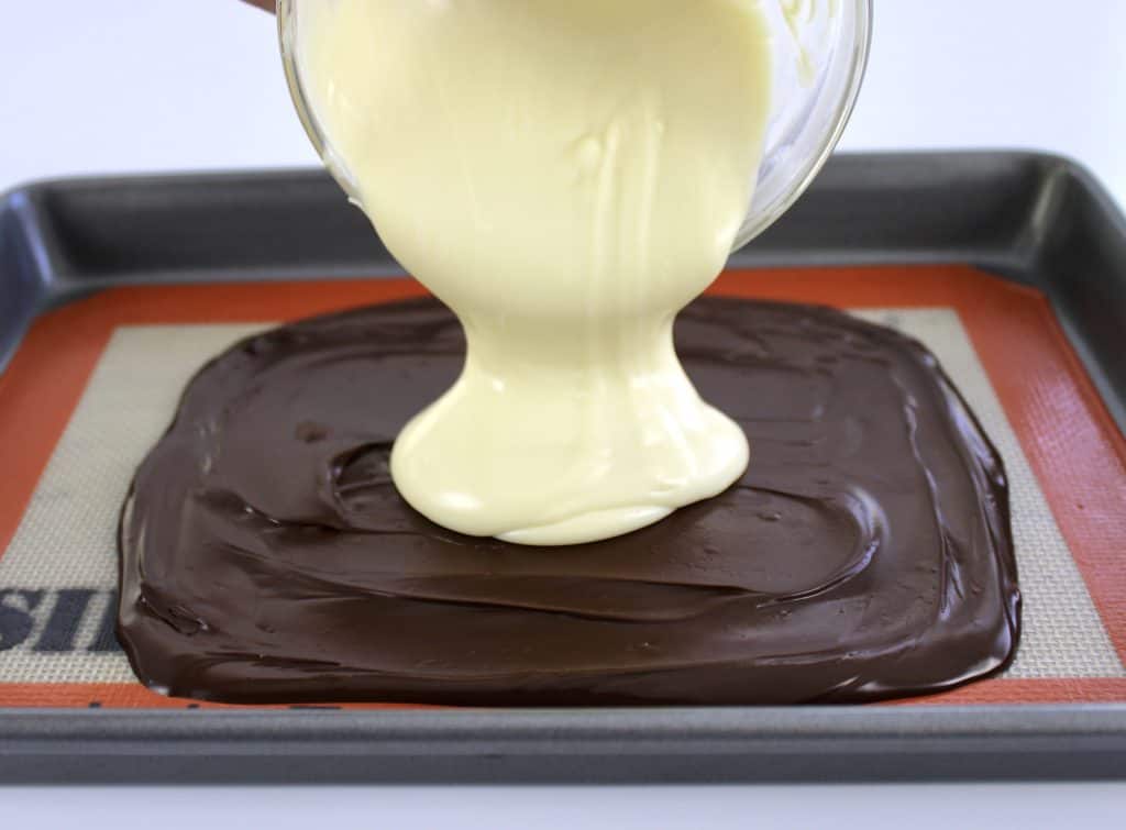 melted white chocolate being poured over chocolate on Silpat