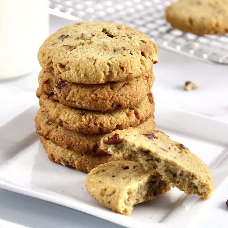 stack of butter pecan cookies on white plate with one broken cookie