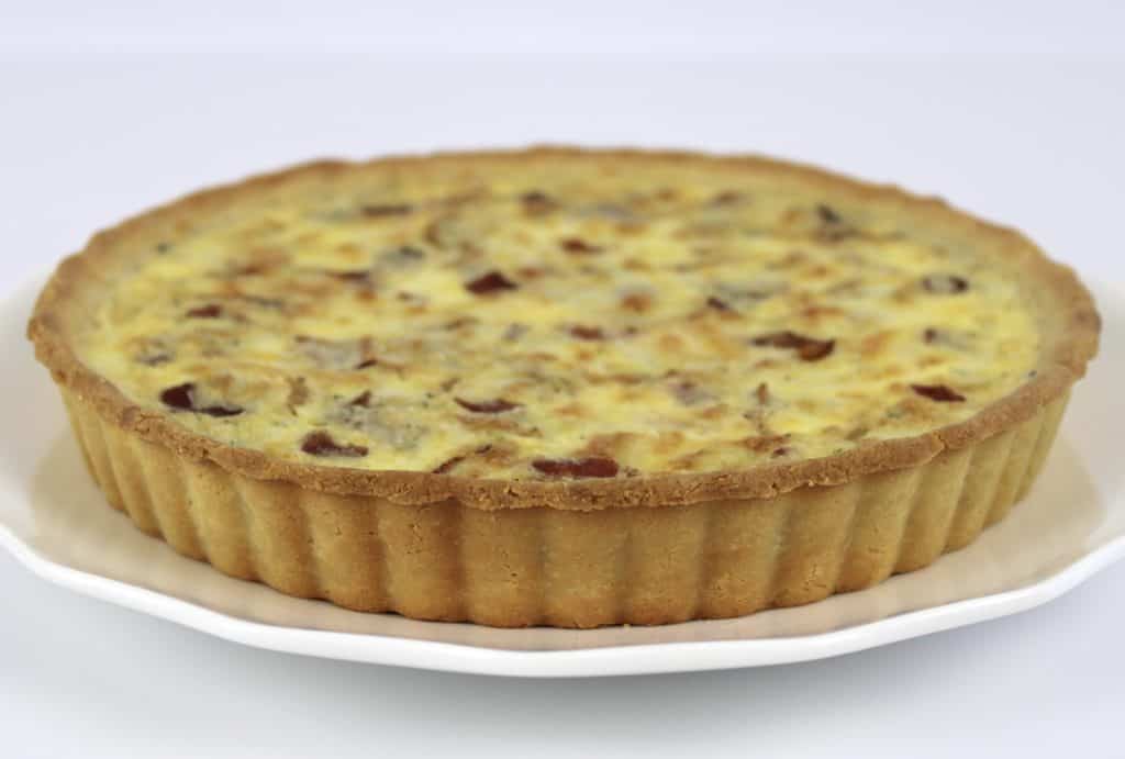 side view of quiche lorraine on white plate