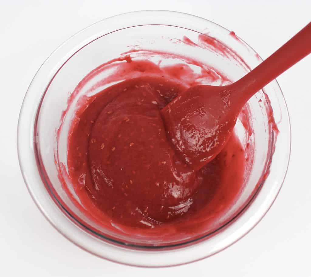 raspberry jam in glass bowl with red spatula