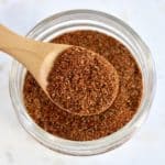 taco seasoning mix in glass jar with wooden spoon holding up some