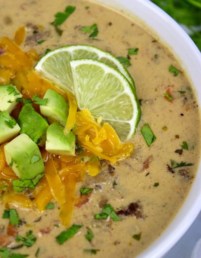 bowl of taco soup with avocado cheese and lime slices on top