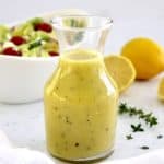 Lemon Vinaigrette in glass jar with salad and lemons in background