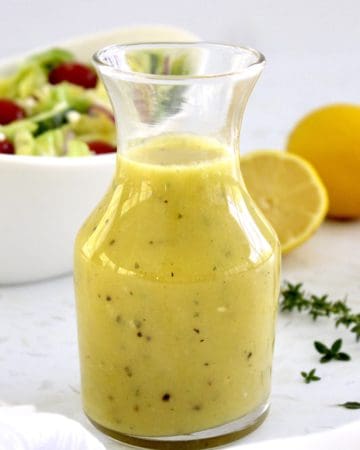 Lemon Vinaigrette in glass jar with salad and lemons in background
