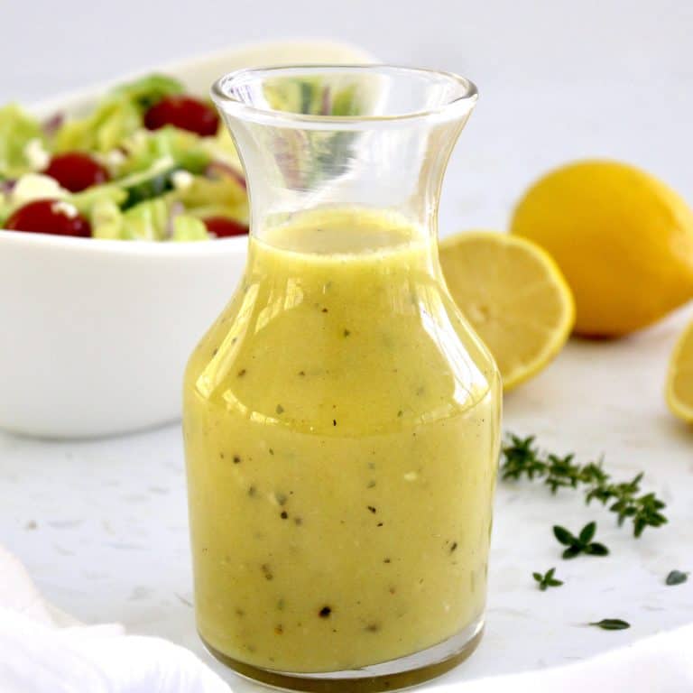 Lemon Vinaigrette in glass jar with salad and lemons in background