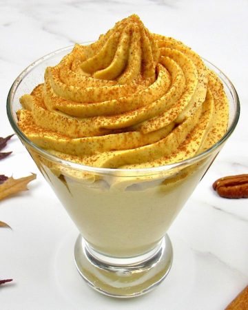 Pumpkin Cheesecake Mousse in fancy glass with pecans in the background