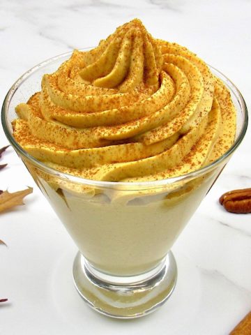 Pumpkin Cheesecake Mousse in fancy glass with pecans in the background