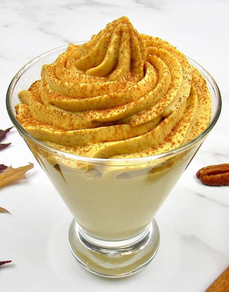 Pumpkin Cheesecake Mousse in fancy glass with pecans in the background