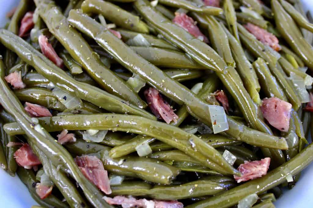 closeup of green beans with chunks of ham and onion