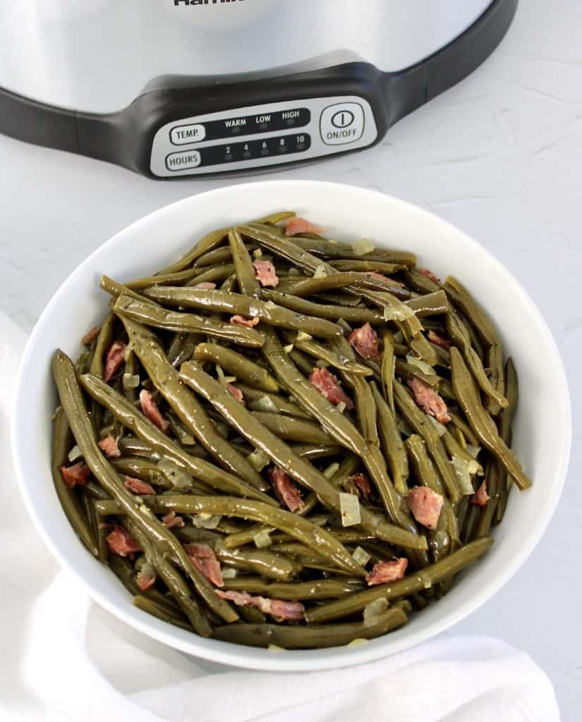 green beans with ham in white bowl crockpot in background