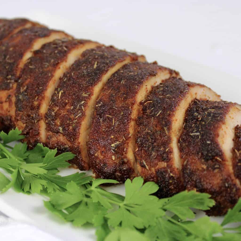 pork tenderloin with seasoned crust sliced on white plate