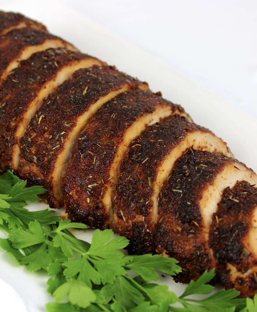 pork tenderloin with seasoned crust sliced on white plate