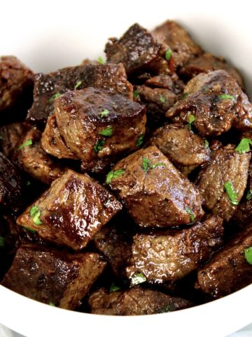 Garlic Butter Steak Bites in white bowl with parsley garnish