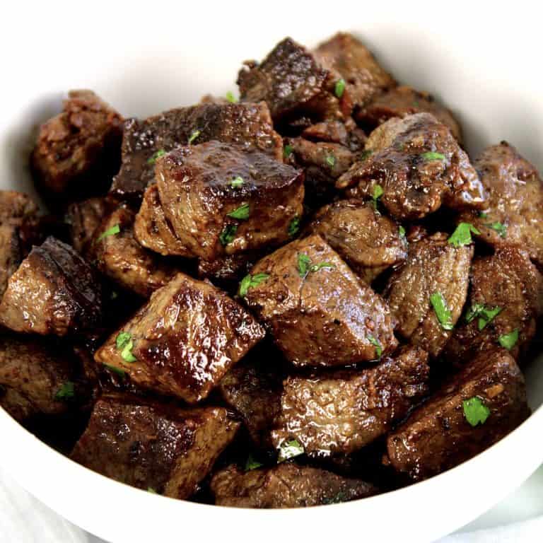 Garlic Butter Steak Bites in white bowl with parsley garnish