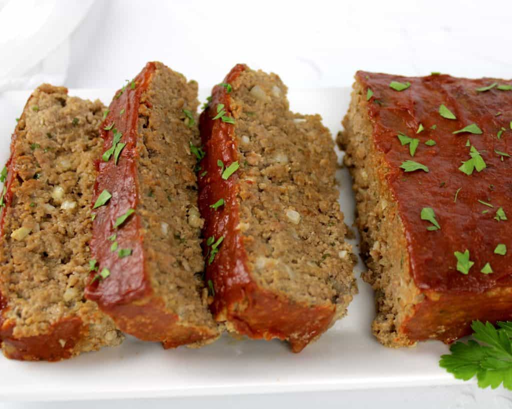 closeup side view of 3 slices of meatloaf on white plate
