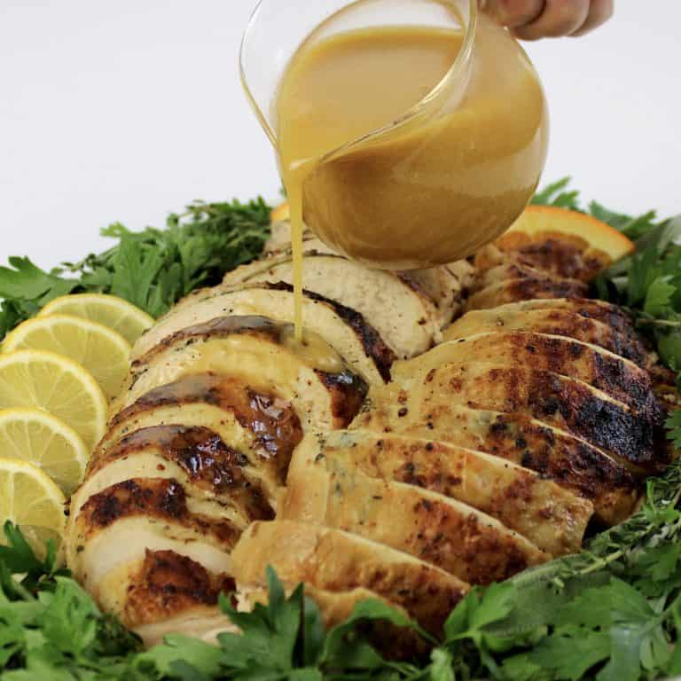 sliced turkey on platter with gravy being poured over top