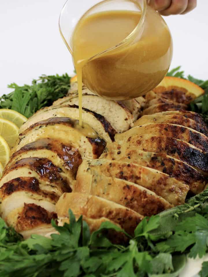 sliced turkey on platter with gravy being poured over top